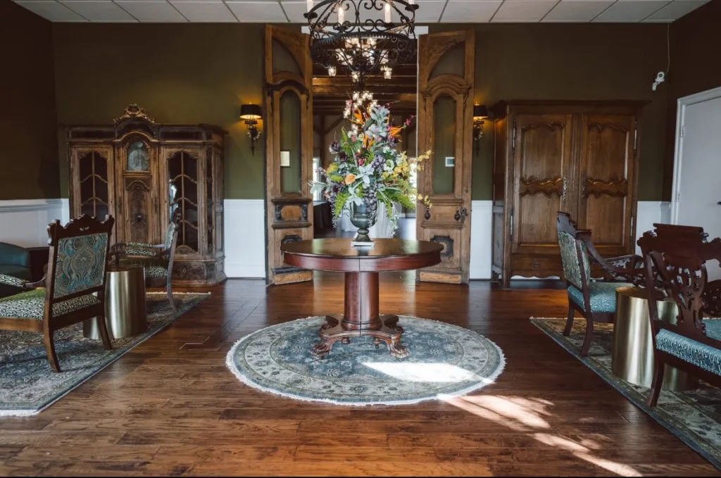 The stylish, high-ceilinged atrium entrance to the Stevenson Ridge Lodge (Spotsylvania wedding venue), featuring historic wooden cabinets, plush seating, and a grand centerpiece under an iron chandelier.